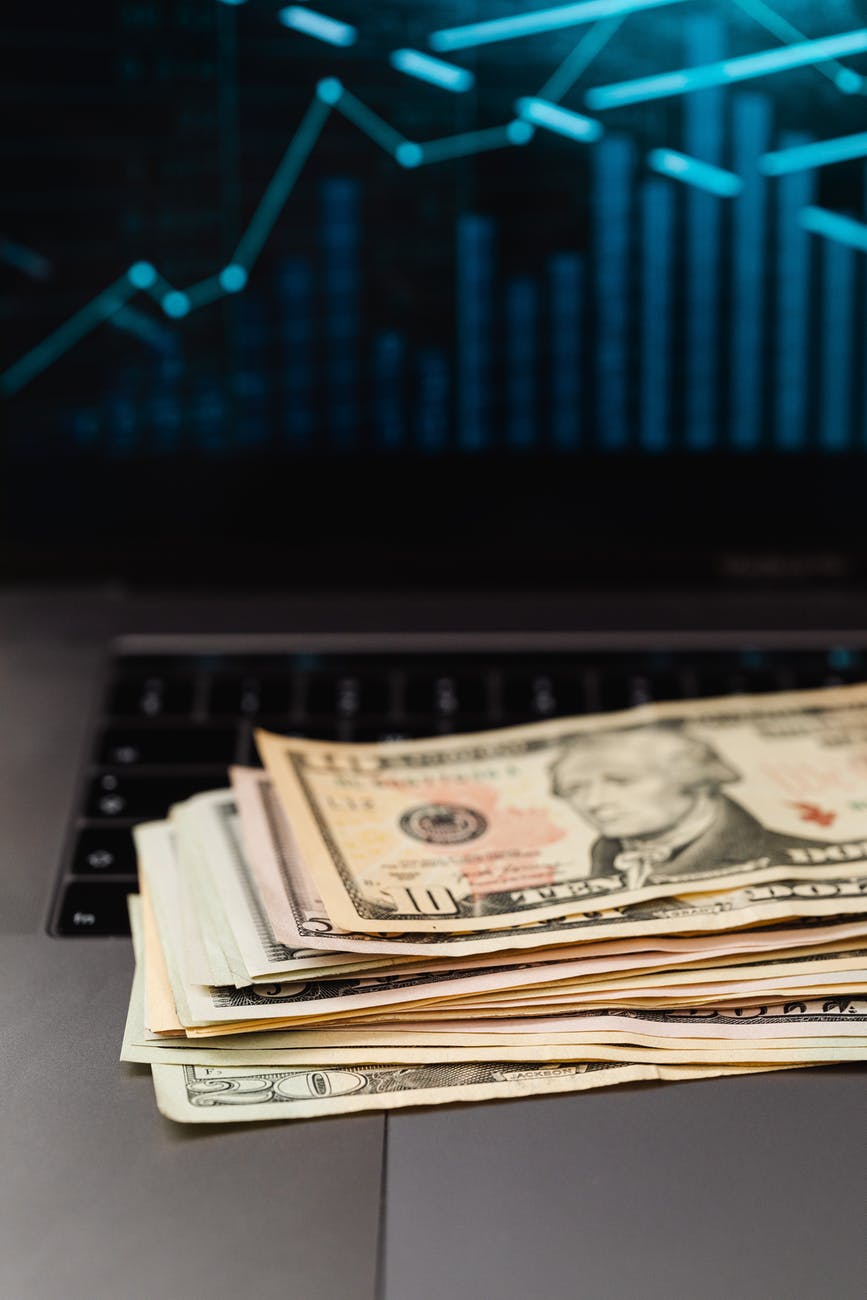 stack of us dollar bills on black and gray laptop