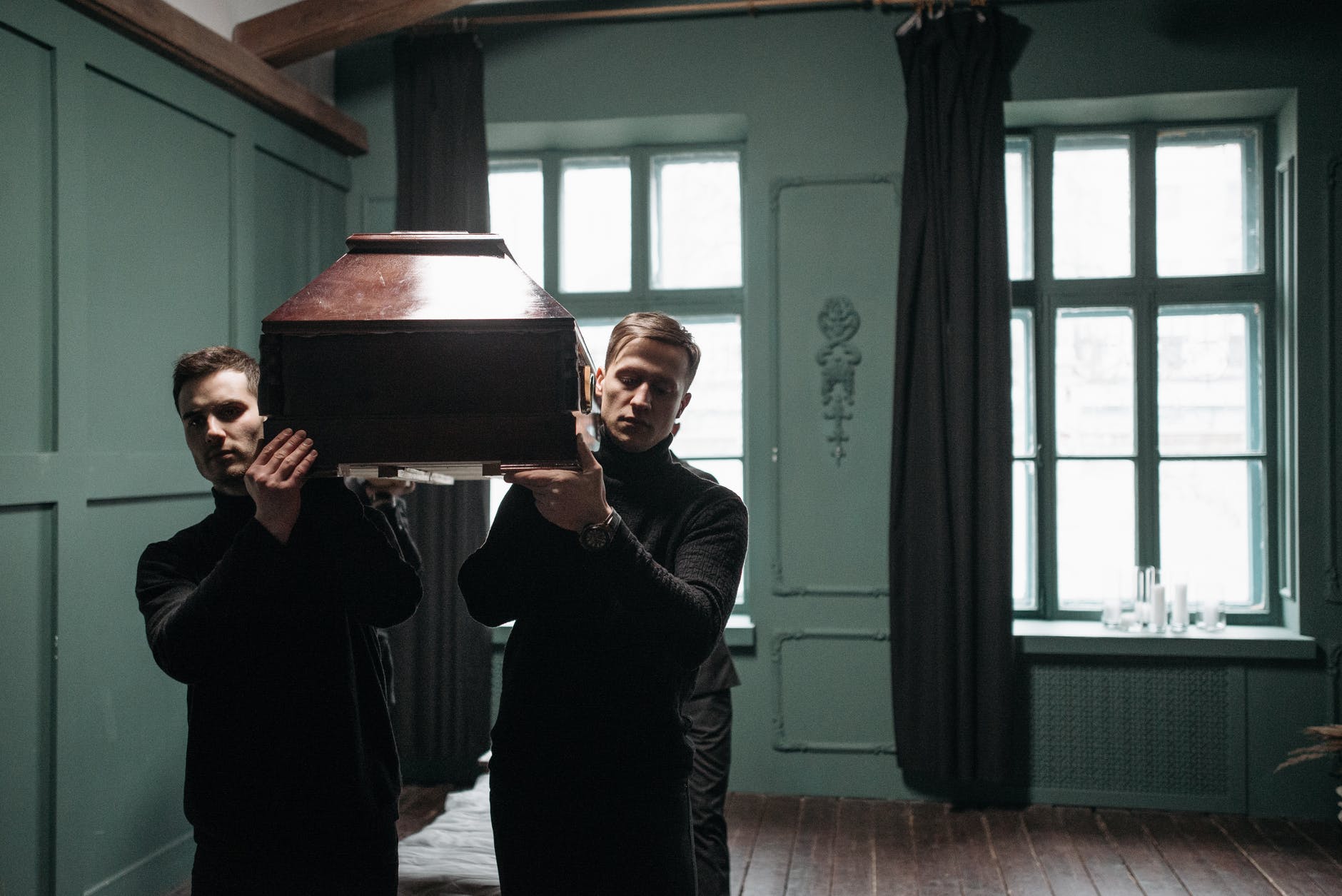 a group of men in black long sleeve shirt carrying a wooden coffin