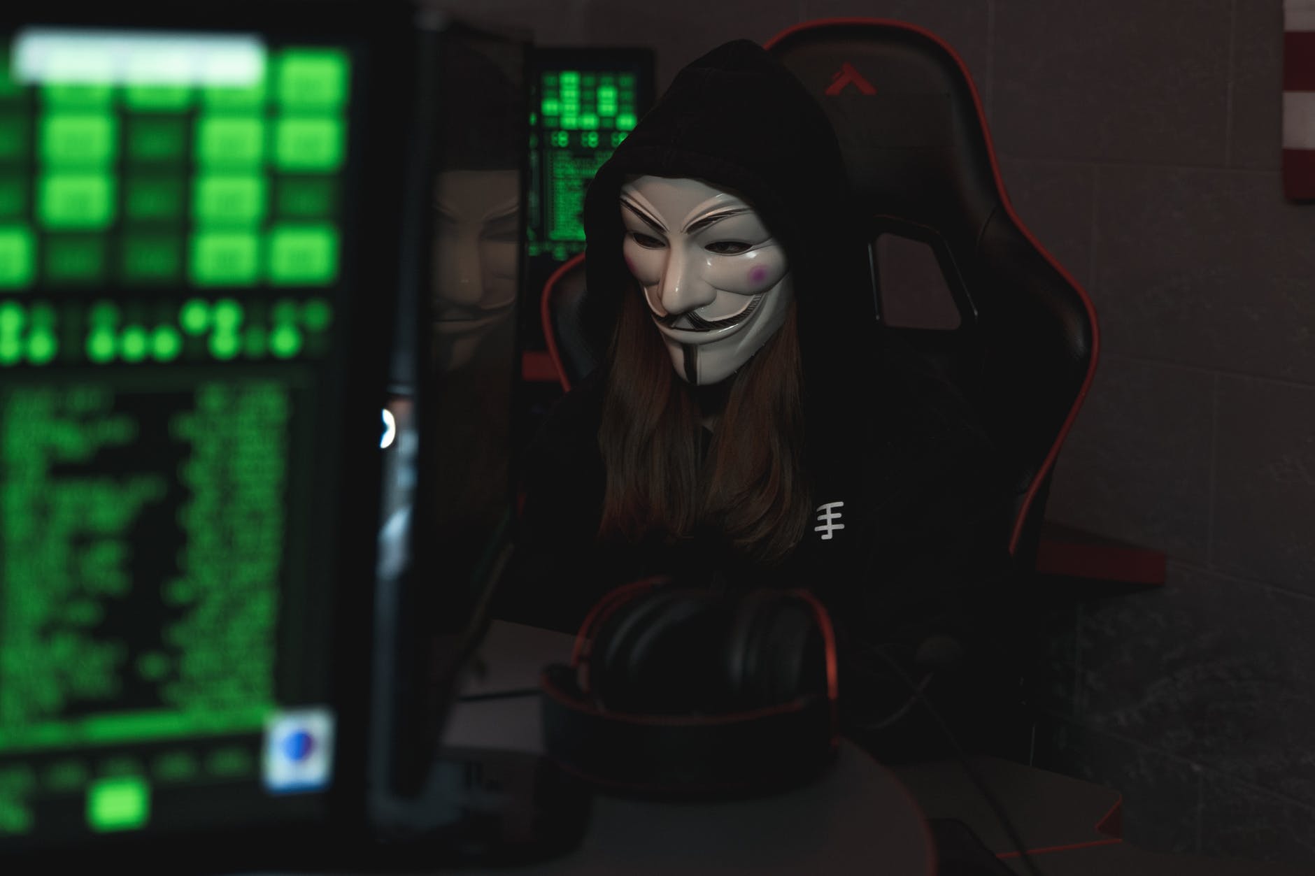 person with mask sitting while using a computer