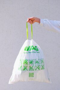 person holding white and green plastic bag