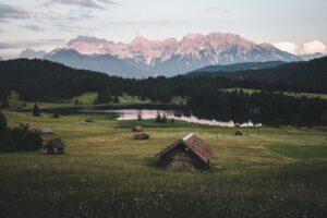 brown wooden house on green grass field near green trees and mountains