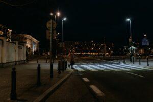 a man in brown coat crossing on the street at night