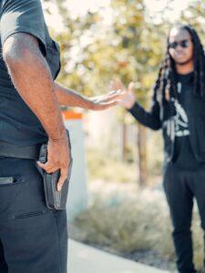 a police man holding his gun while arresting a man