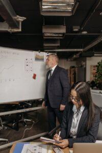 man in black suit jacket standing beside white board