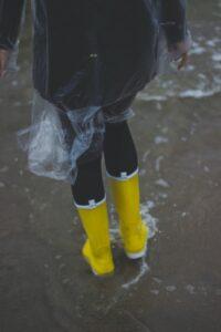 person wearing clear plastic raincoat and pair of yellow rainboots