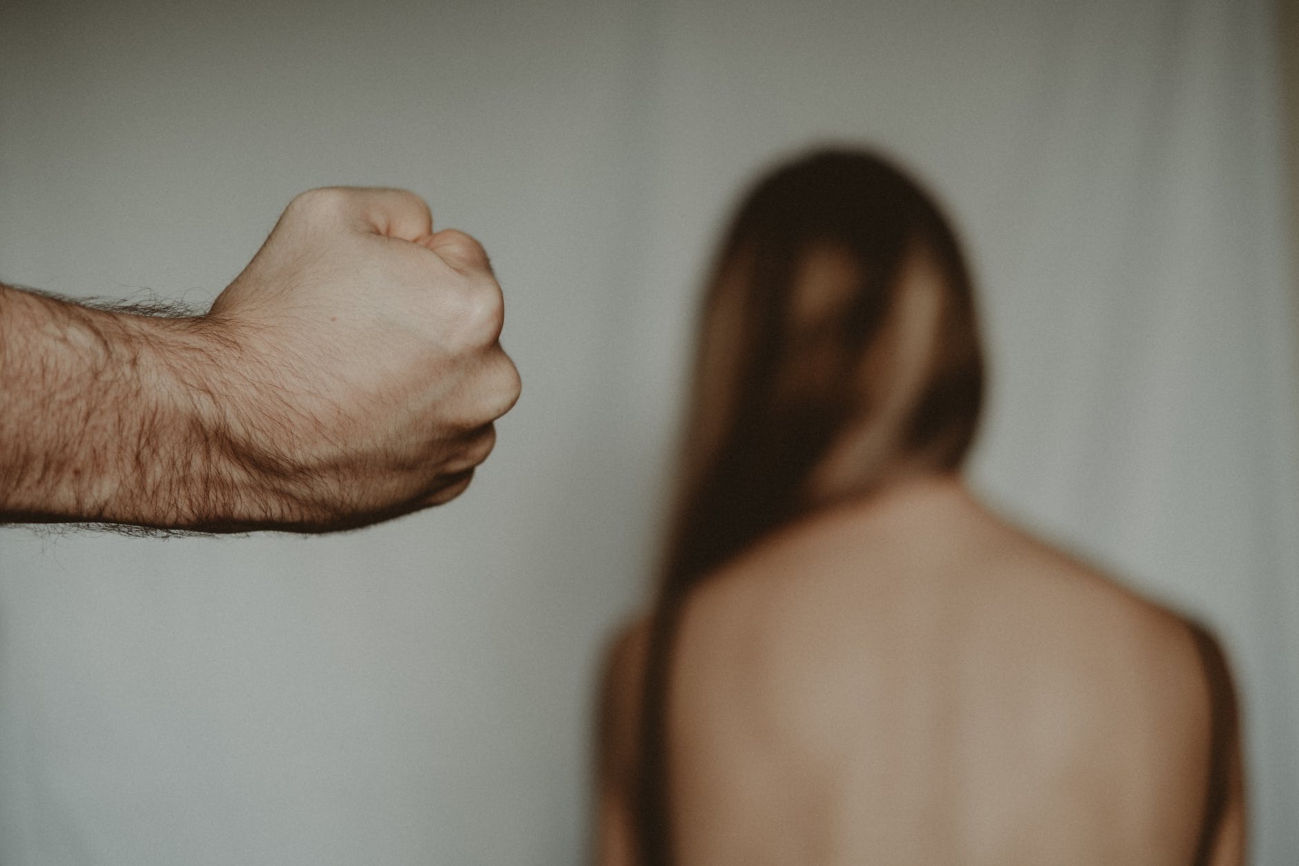 crop man showing fist near anonymous woman