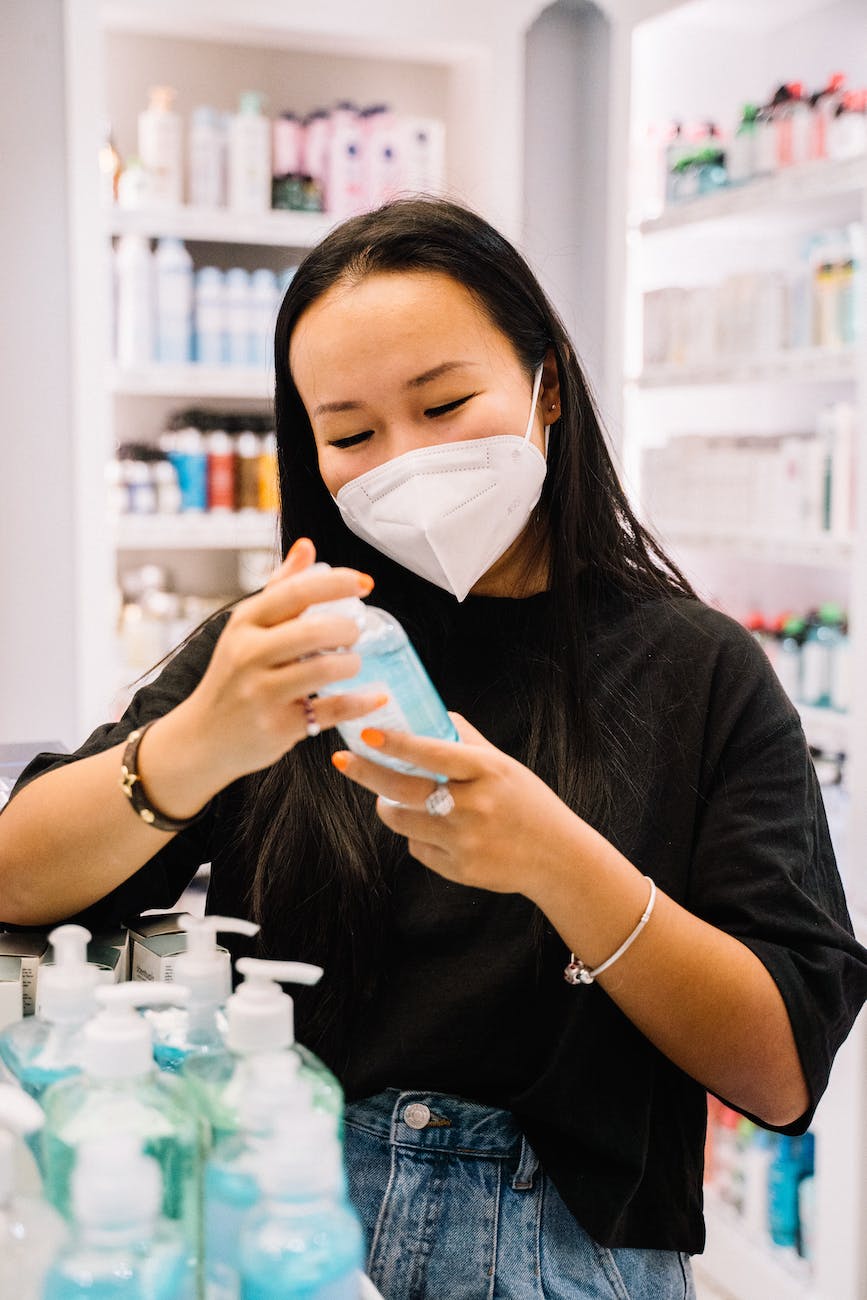 woman with face mask holding a bottle of hand sanitizer