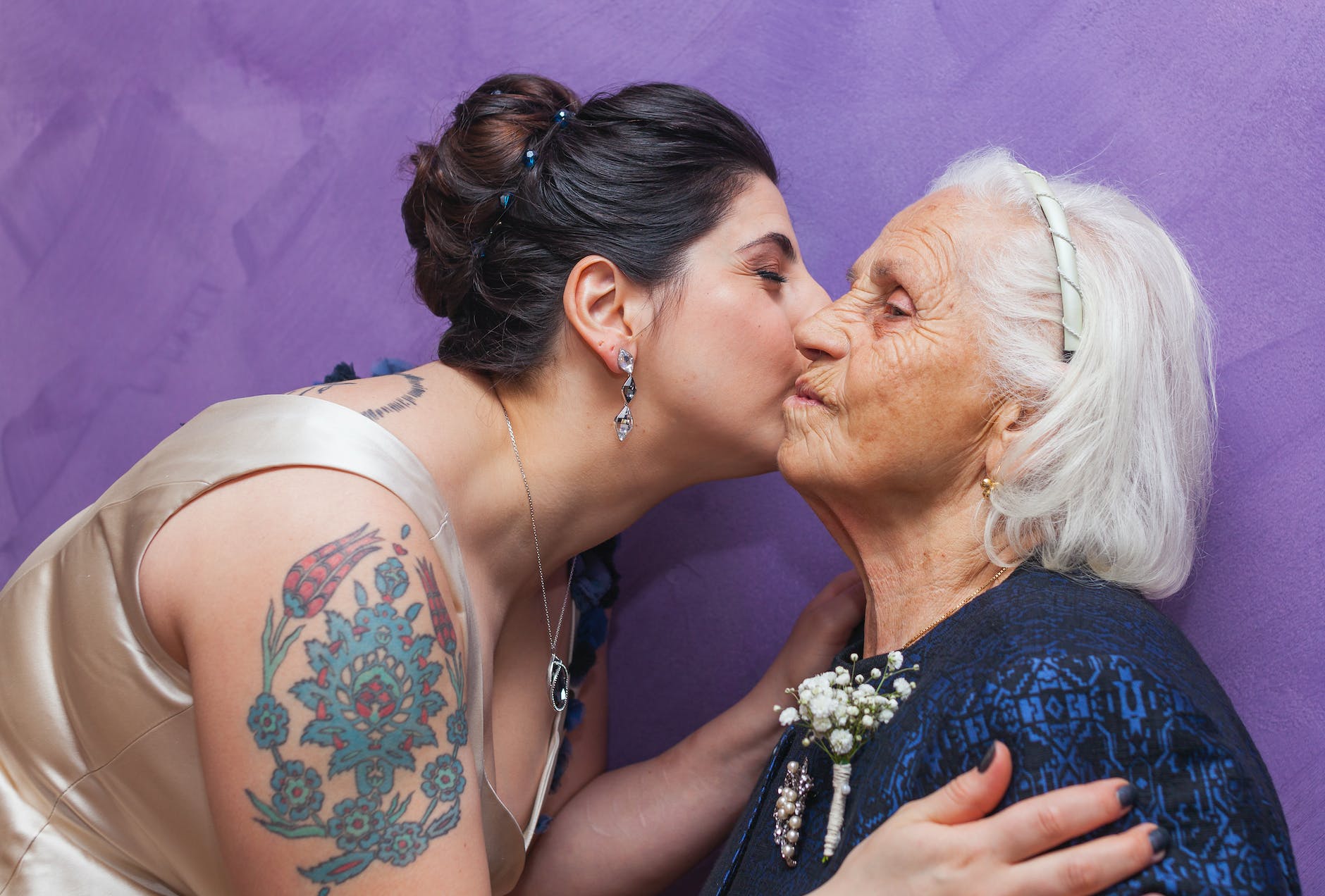 woman kissing woman with boutonniere on chest