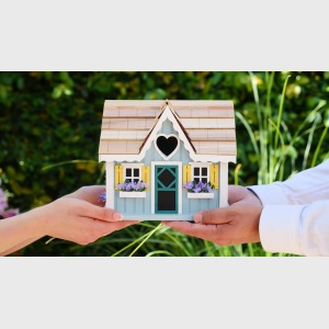 people holding miniature wooden house