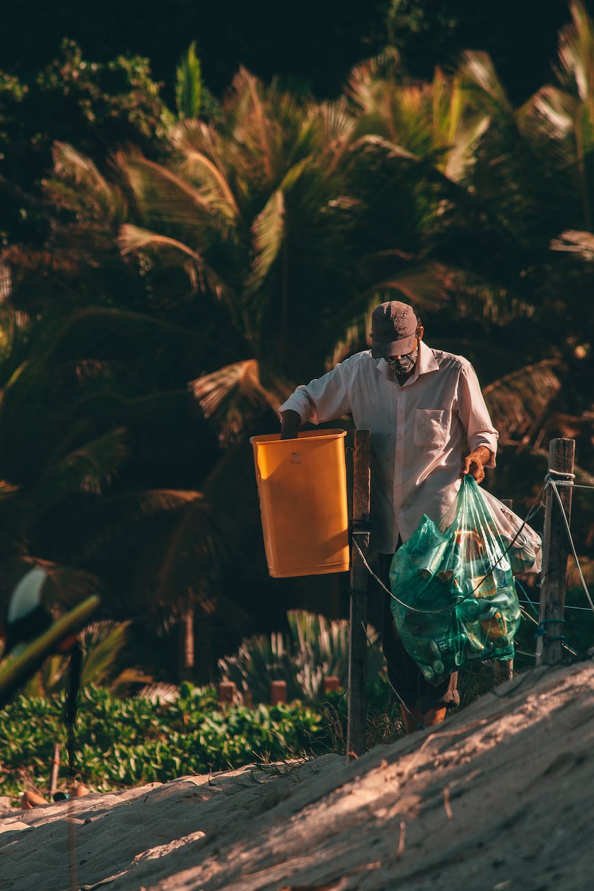 faceless black cleaner collecting garbage from street bin