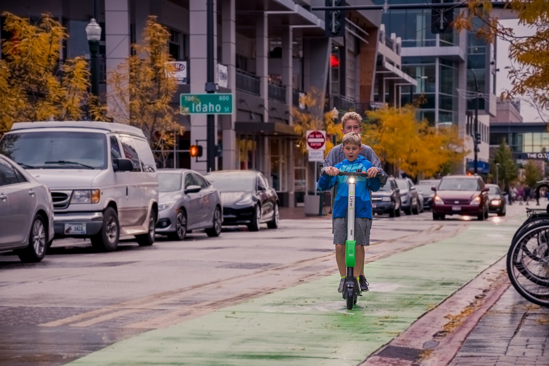 two boys riding lime s scooter on street