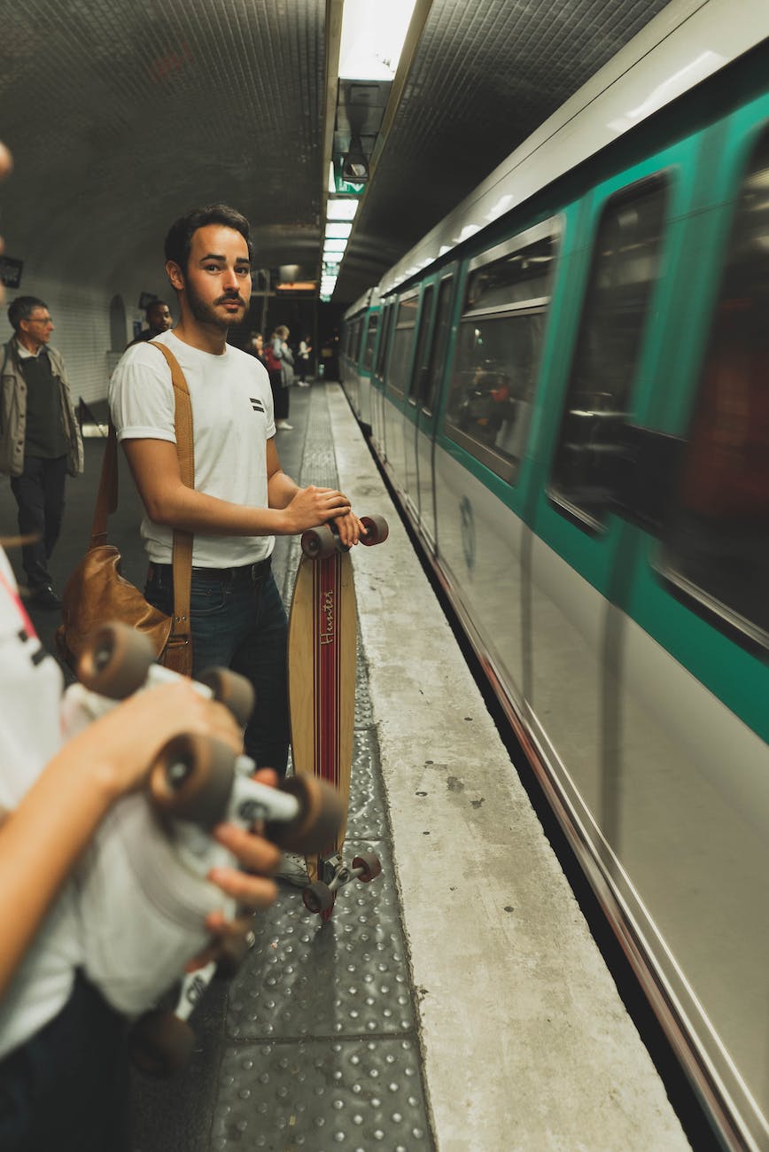 a man holding a skateboard waiting on a subway station