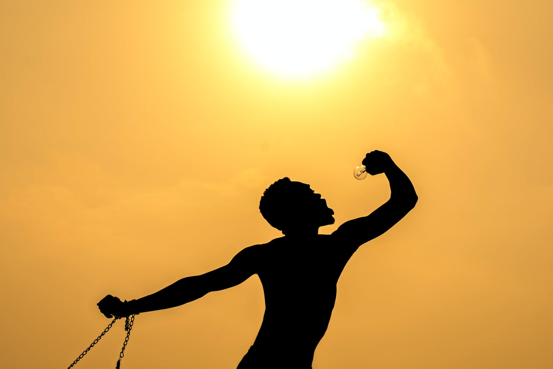 unrecognizable man with bulb against sundown sky