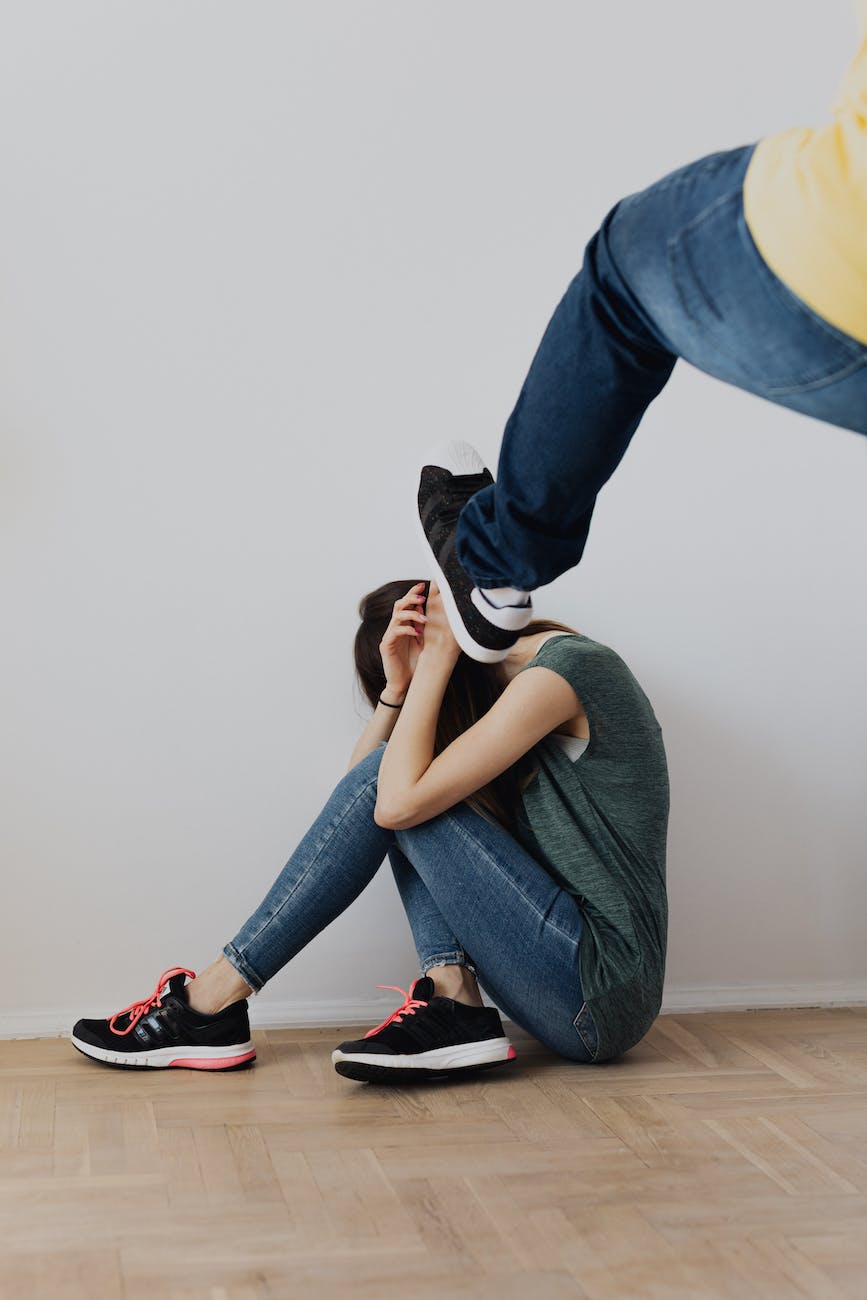 man beating woman sitting on floor