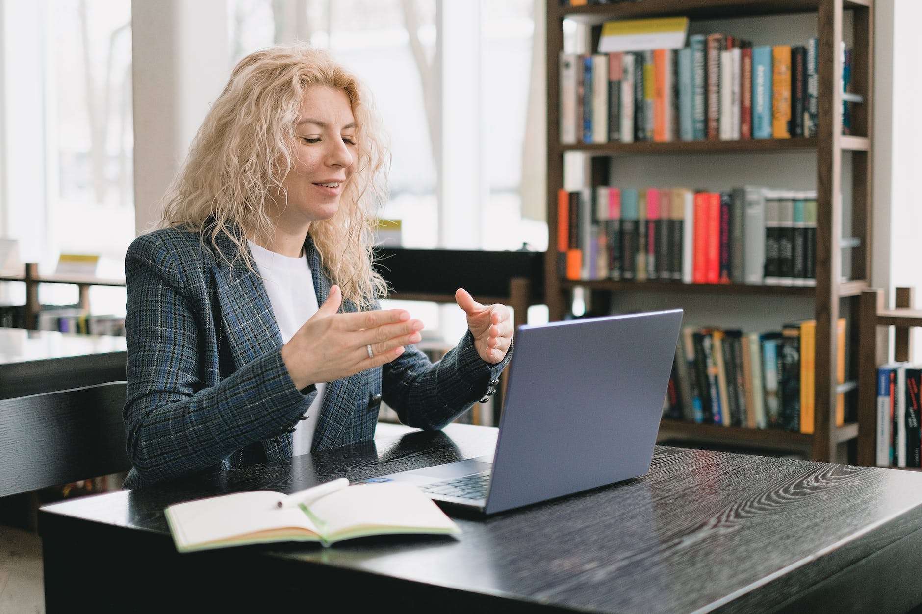 smiling woman having video chat via laptop in library