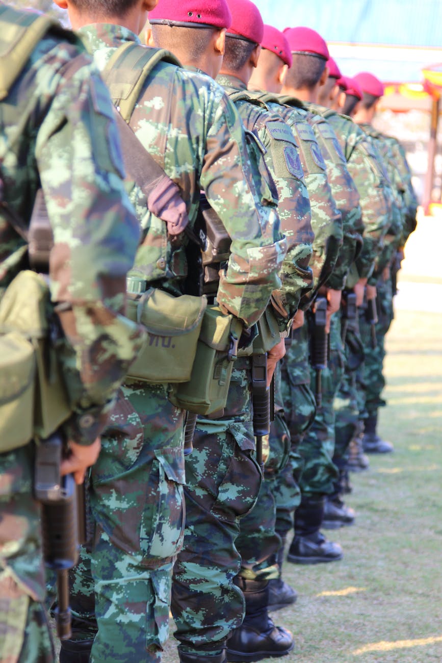 people wearing green and brown camouflage military suit while standing holding rifles