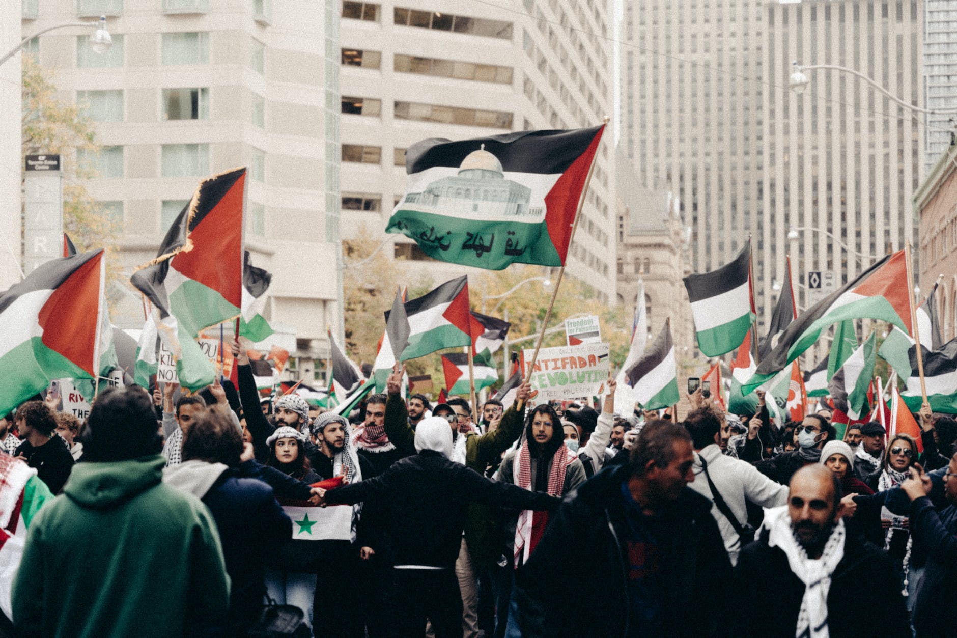 people holding palestinian flags protesting on the street