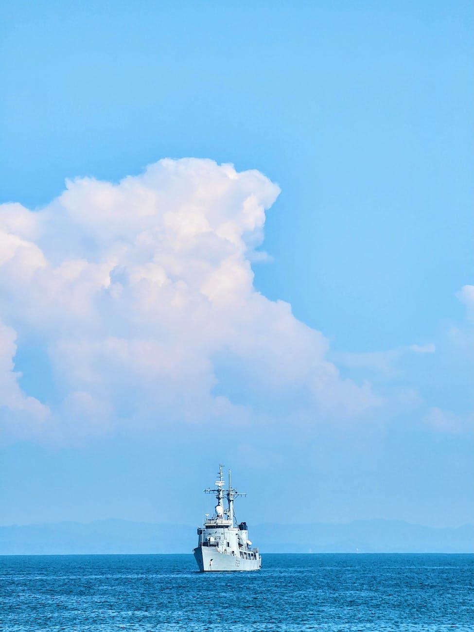 a ship on the sea in the horizon under blue sky