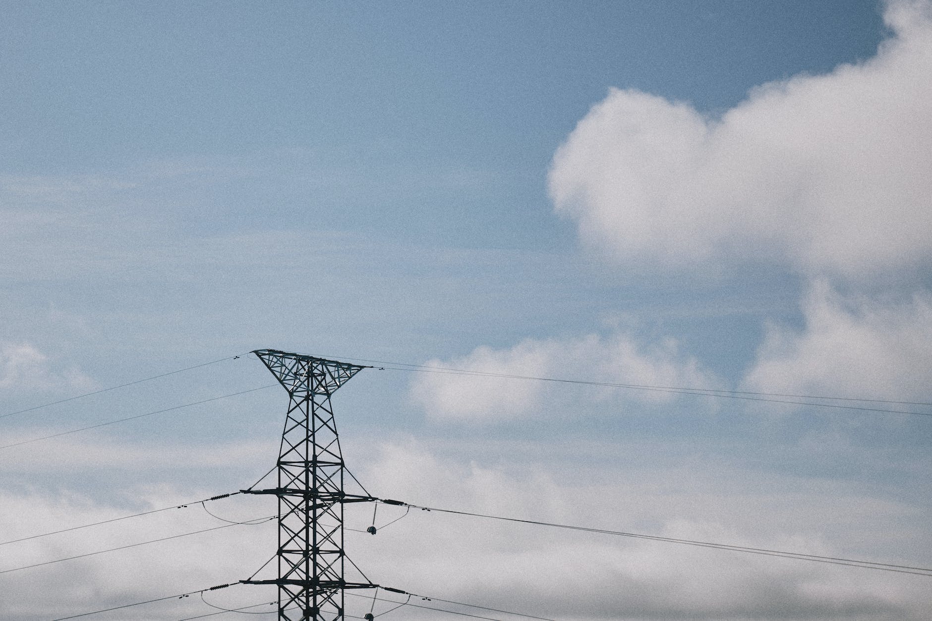 view of an electricity pole and lines against blue sky with white clouds