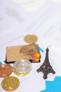 coins bank cards and a miniature eiffel tower on paper documents