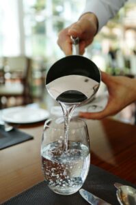 person pouring water on glass